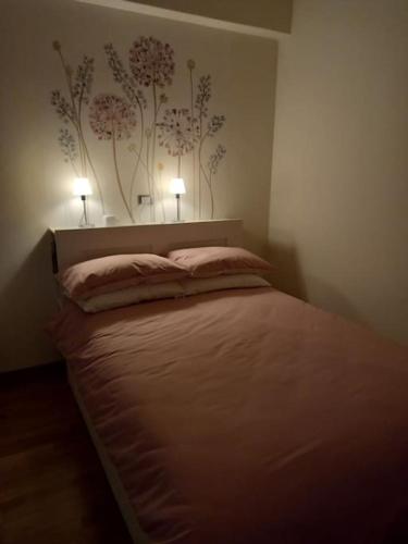a bedroom with a bed with two lights on the wall at Ossola Bella la tua casa in Domodossola
