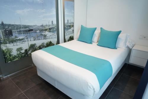 a white bed with blue pillows in a room with a window at Hotel 54 Barceloneta in Barcelona