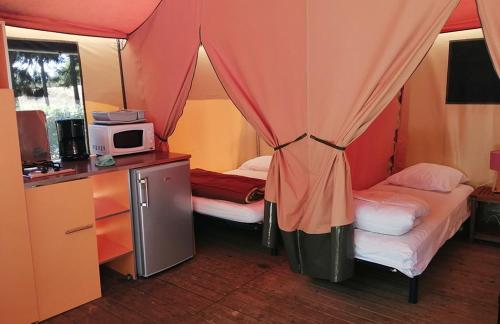 Cette petite chambre comprend deux lits et un four micro-ondes. dans l'établissement Camping les Portes du Perche, à Mamers