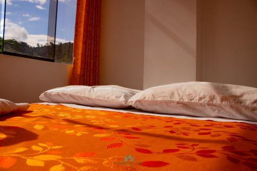 zwei weiße Kissen auf einem Bett mit einer orangefarbenen Decke in der Unterkunft Hinkiori Inn - Hotel Manu in Pillcopata
