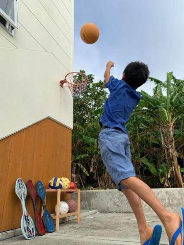 a young boy is jumping to catch a basketball at お子様連れ&動物好き大歓迎！産みたての卵を収穫体験できる宿 in Nanjo