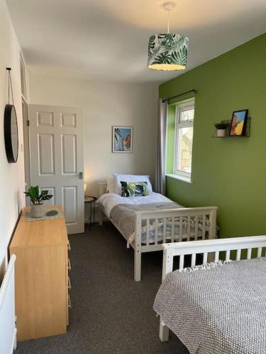 a green bedroom with two beds and a window at 2 bed Central Cardiff Apartment - sleeps five! in Cardiff