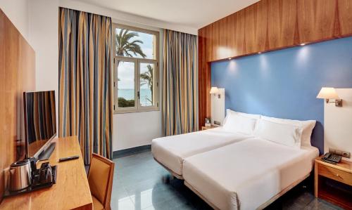 Habitación de hotel con cama y pared azul en Sercotel Kalma Sitges, en Sitges