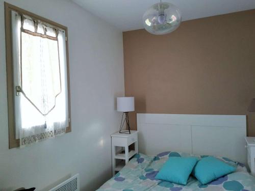 島上黑穆捷的住宿－Appartement L'Herbaudière, 2 pièces, 4 personnes - FR-1-224B-71，一间卧室配有一张带蓝色枕头的床和一扇窗户。