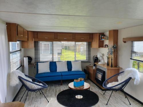 - un salon avec un canapé bleu et deux chaises dans l'établissement CS 61 - Vakantiepark Callassande, à Callantsoog