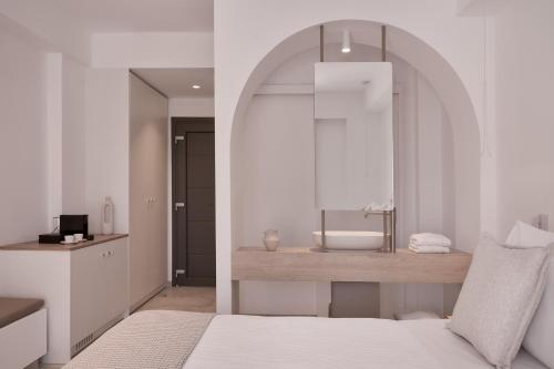 a white bedroom with a bed and a mirror at Isida Andros in Agios Petros