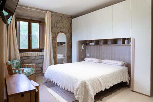 a bedroom with a large white bed and a chair at Le Colline di Giulia - Mini Casa ai piedi della collina in Venarotta