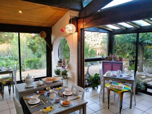 a dining room with tables and chairs and windows at Chambre Indépendante Piscine, Parc, Cuisine... in Brézilhac