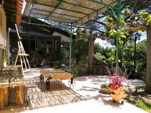 a patio with a wooden bench and a pergola at Chambre Indépendante Piscine, Parc, Cuisine... in Brézilhac