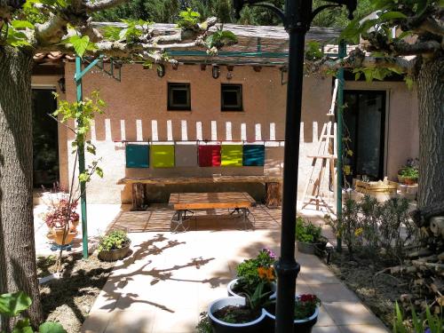 a patio with a wooden bench in front of a house at Chambre Indépendante Piscine, Parc, Cuisine... in Brézilhac