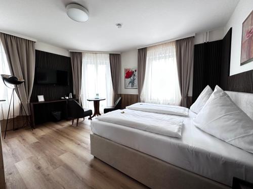 コンスタンツにあるホテル ビルガー エックの大きなベッドとデスクが備わるホテルルームです。