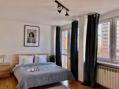- une chambre avec un grand lit et des rideaux noirs dans l'établissement oompH Warsaw Downtown Apartments, à Varsovie