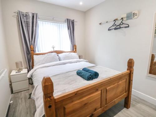 a bedroom with a bed with a wooden frame and a window at Sea La Vie in Rhyl