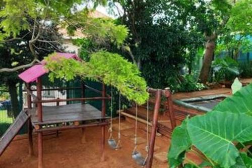 einen Garten mit einem Holztisch und einer Bank in der Unterkunft Harbour View House in Durban