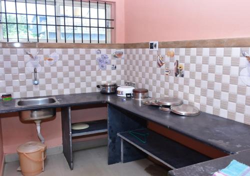 uma cozinha com um lavatório e um balcão com panelas e frigideiras em Sri Kaveri Homestay em Madikeri