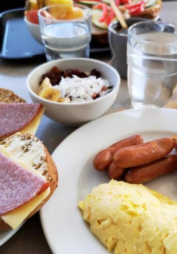 a table with a plate of food with sausage and eggs at Comfort Hotel Eskilstuna in Eskilstuna