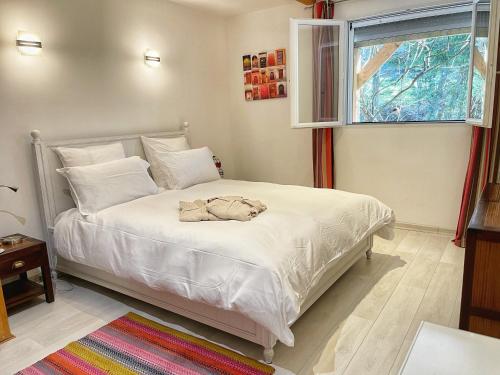 een slaapkamer met een bed met witte lakens en een raam bij Appartement au calme avec terrasse verdoyante entre Annecy et Genève in Villy-le-Pelloux