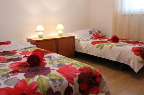 a bedroom with two beds with red flowers on them at Apartment Fuma in Marčana