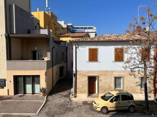ein kleines gelbes Auto, das vor einem Gebäude parkt in der Unterkunft Casetta sul Mare in Fano