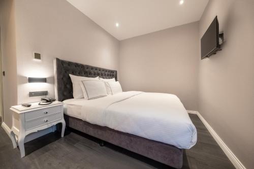 a bedroom with a white bed and a night stand with a television at Loop Hotel Bosphorus İstanbul in Istanbul