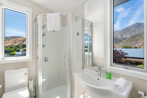 a white bathroom with a shower and a sink at Heavenly on Hope - Lake Hayes Holiday Home in Queenstown