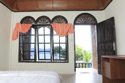 a bedroom with a bed and a large window at SONY COTTAGE in Tuk Tuk