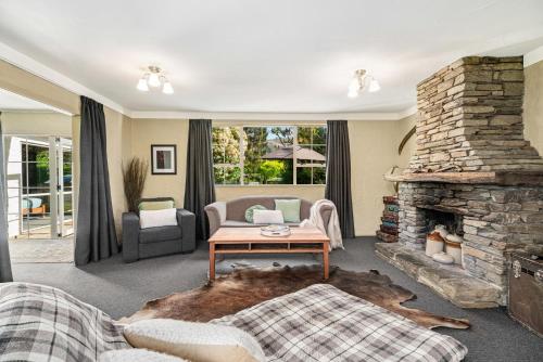 un soggiorno con divano e camino in pietra di Kent Cottage - Arrowtown Holiday Home ad Arrowtown