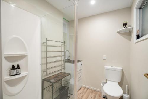 a white bathroom with a toilet and a shower at Albert Town Bach - Wanaka Holiday Home in Wanaka
