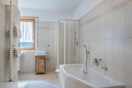 a white bathroom with a tub and a shower at Adlerhorst Rotkehlchen in Santa Valpurga
