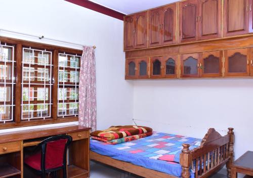 a bedroom with a bed and a desk and a wooden cabinet at Sri Kaveri Homestay in Madikeri