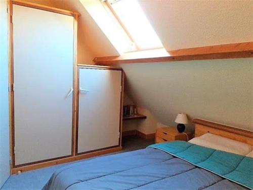 - une chambre avec un lit bleu et une lucarne dans l'établissement Charmante Maison avec Piscine, Tennis, Proche Mer - Idéal Famille - FR-1-392-140, à Batz-sur-Mer