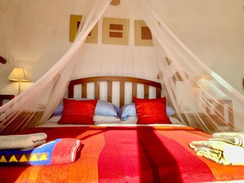 - une chambre avec un lit à baldaquin et des oreillers rouges dans l'établissement Villa & Poolhouse with Private Pool 360 degrees view 'Spinola' in pure nature, à Alozaina