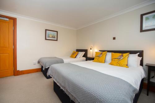 a hotel room with two beds with yellow pillows at Redesdale Arms in Otterburn
