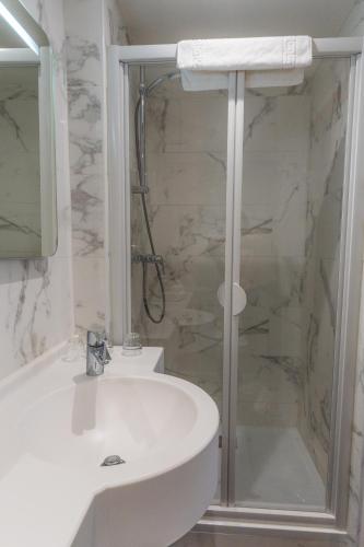 a white bathroom with a shower and a sink at Grand Hôtel de L'Espérance in Lisieux