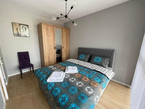 1 dormitorio con 1 cama con colcha azul y silla en Apartments Mir Varna city, en Varna