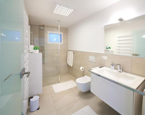 a white bathroom with a sink and a toilet at Tauberperle - Exklusives Ferienapartment in Lauda-Königshofen
