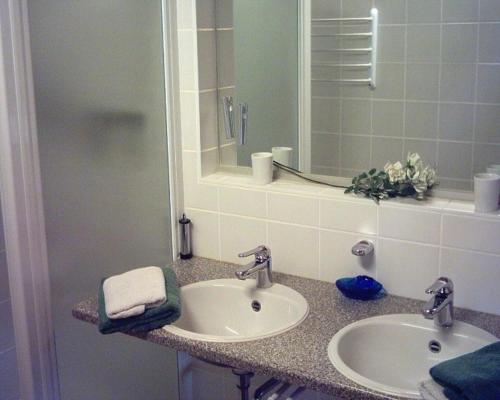 uma casa de banho com 2 lavatórios e um espelho em Appartement Schelhas em Prien am Chiemsee