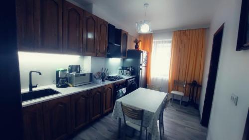 a kitchen with wooden cabinets and a table and a microwave at On Khimshiashvili Apartment in Batumi