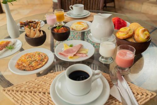 a glass table topped with plates of food and drinks at Almai Cumbuco in Cumbuco