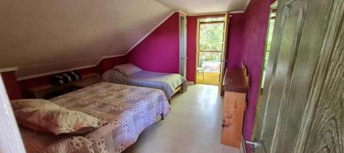 a bedroom with two beds in a room with purple walls at Hostal Macal in Talca