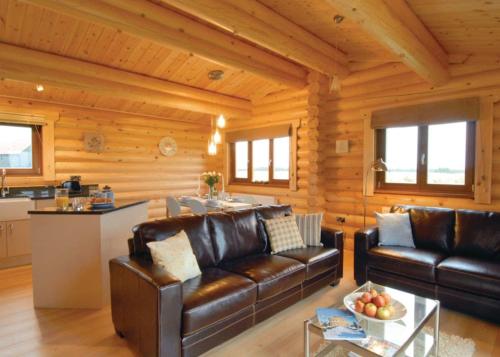 a living room with leather furniture in a log cabin at Laxfield Lodges in Laxfield