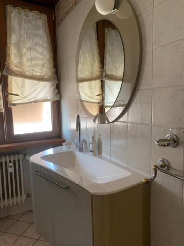 ein Badezimmer mit einem weißen Waschbecken und einem Spiegel in der Unterkunft ARIA DI CASA in Verona