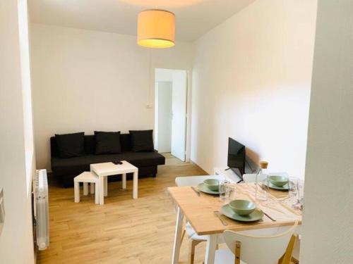 ein Wohnzimmer mit einem Tisch und einem schwarzen Sofa in der Unterkunft Appartement plein centre in Paray-le-Monial