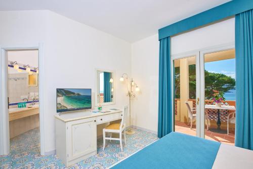 a bedroom with a bed and a desk with a mirror at Hotel Biodola in Portoferraio