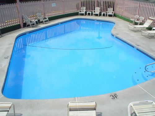 een groot blauw zwembad met stoelen in een hotel bij Avenue Motel Wenatchee in Wenatchee