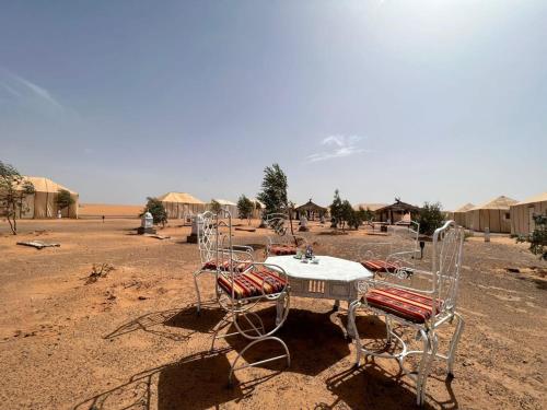 a table and chairs in the middle of the desert at Your journey starts here in Merzouga