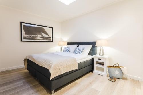 1 dormitorio con 1 cama grande y pared blanca en Strandvilla Apartment Hafenglück, en Büsum