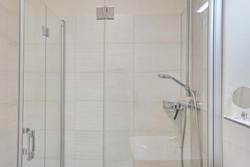 una ducha con una puerta de cristal junto a un lavabo en Helios, en Büsum