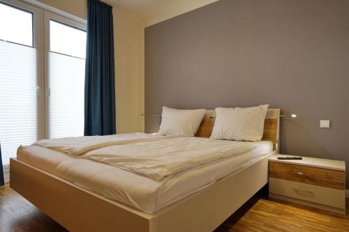 Un dormitorio con una gran cama blanca con ventana. en Helios, en Büsum