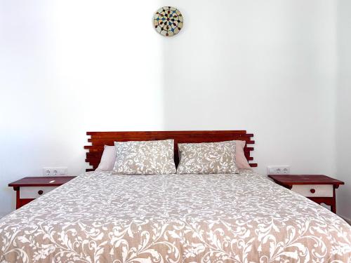 een slaapkamer met een bed met 2 tafels en een klok bij La Casita de Los Alambiques in Chiclana de la Frontera